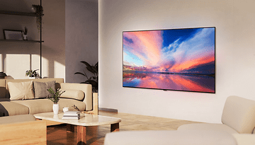 Ein modernes Wohnzimmer mit einem LG OLED77B4 Fernseher, der einen bunten Sonnenuntergang über Wasser zeigt.