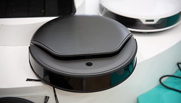 Ein schwarzer, robotischer Staubsauger, der ausgestellt ist, mit einem eleganten Design und glänzender Oberfläche.