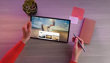 Eine Person benutzt ein Lenovo IdeaTab Pro Tablet mit einem Stylus, studiert mit Notizen und einer Pflanze auf dem Tisch.