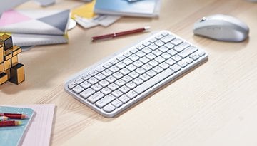 Eine Logitech MX Keys Mini-Tastatur für Mac auf einem Holztisch mit Schreibwaren.