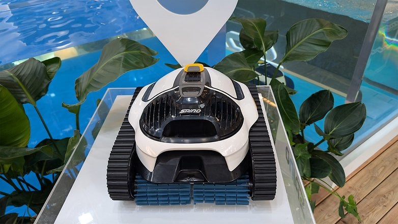 Ein roboter Poolreiniger, der auf einem Stand mit einem blauen Pool im Hintergrund ausgestellt ist. Ein roboter Poolreiniger, der auf einem Stand mit einem blauen Pool im Hintergrund ausgestellt ist.