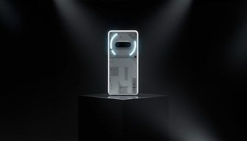 Ein weißes Smartphone mit einzigartigem Design, auf einem Podest unter einem Scheinwerfer ausgestellt.