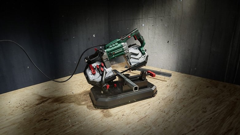 Eine Parkside Metallbandsäge auf einer Holzoberfläche, mit einem Stromkabel und nahegelegenen Metallstücken. Eine Parkside Metallbandsäge auf einer Holzoberfläche, mit einem Stromkabel und nahegelegenen Metallstücken.
