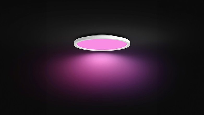 Eine runde Deckenleuchte, die pinkes Licht vor einem dunklen Hintergrund ausstrahlt. Eine runde Deckenleuchte, die pinkes Licht vor einem dunklen Hintergrund ausstrahlt.