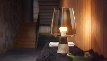 Eine Philips Hue E27 weiß Ambiance Lampe mit Glasschirm auf einem Holztisch in einem modernen Flur.