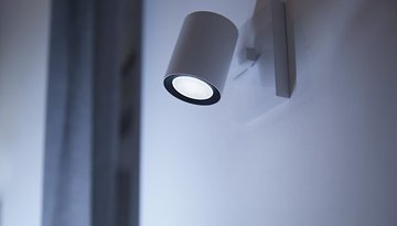 Ein Philips Hue White Ambiance GU10 Spotlicht, das an einer Wand montiert ist und sanftes weißes Licht abgibt.