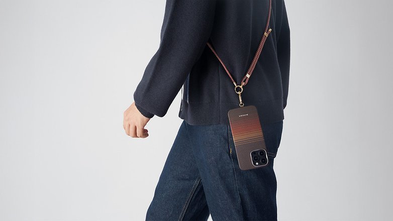 Eine Person trägt einen dunklen Pullover und Jeans, während sie ein iPhone 16 mit dem Pitaka Tactile Woven Case an einem Gurt um die Taille trägt.