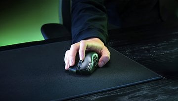 Eine Hand verwendet eine Razer Naga V2 Hyperspeed Gaming-Maus auf einem schwarzen Mauspad.