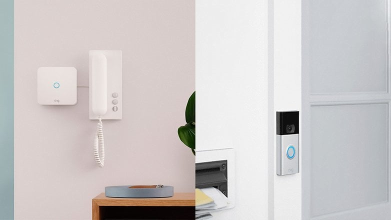 Un interphone Ring et une sonnette vidéo installés sur un mur, avec une plante et une boîte aux lettres à proximité.