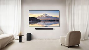 Ein modernes Wohnzimmer mit einer Samsung-Soundbar unter einem Fernseher, der eine Berglandschaft zeigt.
