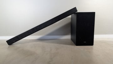 Eine Samsung HW-B540 Soundbar, die schräg neben ihrem Subwoofer auf einer hellen Oberfläche steht.