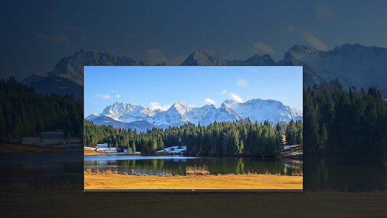 Ein TCL Smart-TV, der eine malerische Landschaft mit Bergen und einem See zeigt. Ein TCL Smart-TV, der eine malerische Landschaft mit Bergen und einem See zeigt.