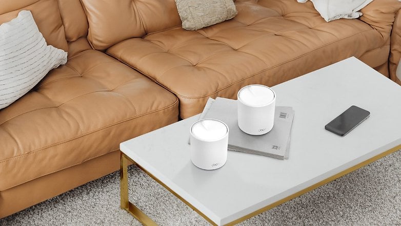 Zwei TP-Link Deco X50 Mesh-Repeater auf einem Couchtisch neben einem Smartphone und Zeitschriften. Zwei TP-Link Deco X50 Mesh-Repeater auf einem Couchtisch neben einem Smartphone und Zeitschriften.