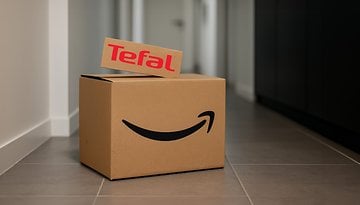 Ein Karton mit einem Amazon-Logo und einem 'Tefal'-Schild oben, in einem Flur platziert.