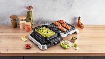 Tefal Optigrill, der Gemüse und gegrillten Lachs auf einer Holzarbeitsplatte zubereitet.