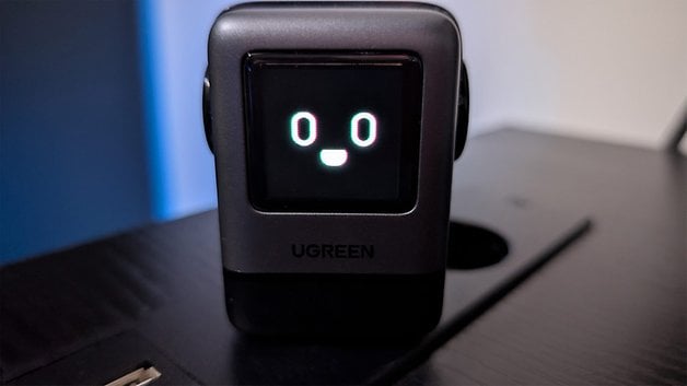 Ugreen Uno 100W device with its digital display showing a smiling face.