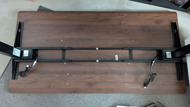 Obenansicht eines Vernal-Schreibtisches mit stabiler Rahmenkonstruktion und sichtbaren Kabeln darunter.