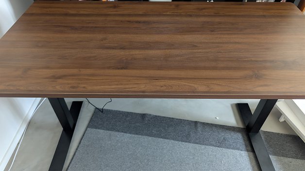 Ein Holztisch mit glatter Oberfläche und schwarzen Beinen, auf einem Teppich platziert.