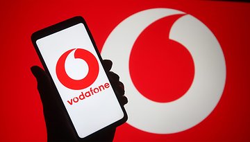 Vodafone-Logo auf einem Smartphone mit großem Logo im Hintergrund.