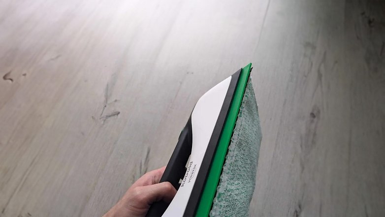 Eine Person hält ein Vorwerk Kobold VG100 Plus Reinigungswerkzeug gegen einen Holzboden.