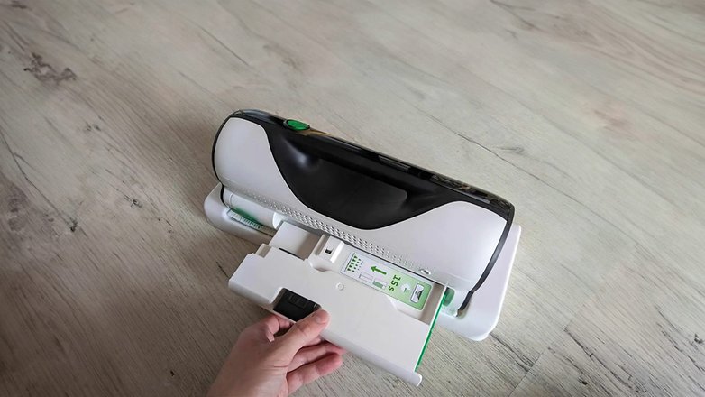Ein Vorwerk Kobold VG100 Plus Staubsauger mit einer Hand, die das abnehmbare Teil hält.