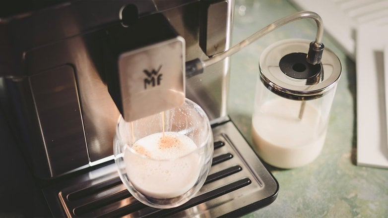 Eine WMF Perfection 660L Kaffeemaschine, die aufgeschäumte Milch in ein Glas ausgibt.