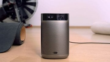 Ein tragbarer XGIMI Mogo 2 Pro Projektor auf einem Holzfußboden mit einer schwarzen Matte in der Nähe.