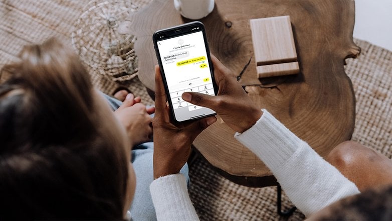 Eine Person verwendet die comdirect-App auf einem Smartphone, um eine Transaktion abzuschließen.