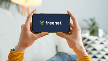 Eine Person hält ein Smartphone mit dem freenet-Logo.