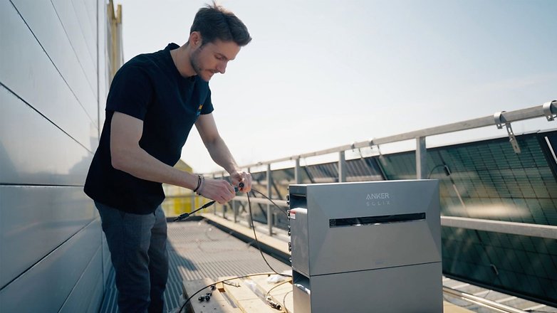 Ein Mann arbeitet an einem Anker Solix 3 Pro-Gerät auf einem Dach. Ein Mann arbeitet an einem Anker Solix 3 Pro-Gerät auf einem Dach.