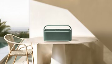 Ein grüner Anker Soundcore Motion X600 Bluetooth-Lautsprecher auf einem Tisch in einer Außenumgebung.