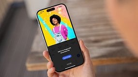 Une personne tient un smartphone affichant l'application Adobe Photoshop avec un design graphique coloré.