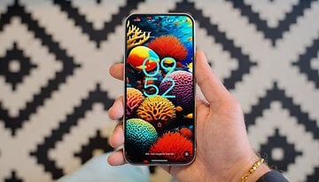 A hand holding a Google Pixel 9 smartphone displaying a colorful coral-themed wallpaper and the time 09:52.