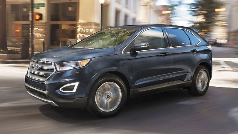 A blue Ford SUV driving through a city street. A blue Ford SUV driving through a city street.