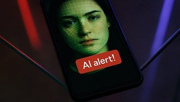 A smartphone displaying a face with a green grid overlay and an 'AI alert!' message.
