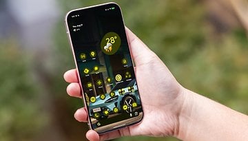 A person holding a Google Pixel 9 Pro smartphone displaying app icons and a weather widget showing 28°C.