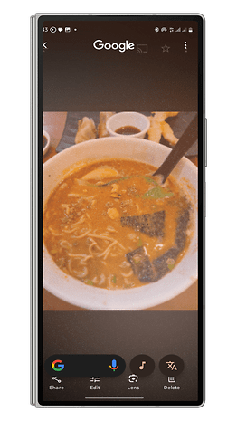 Un smartphone affichant un bol de ramen avec divers ingrédients et une interface Google.