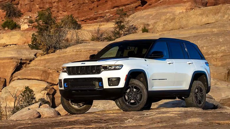 A white Jeep SUV parked on rocky terrain with red cliffs in the background. A white Jeep SUV parked on rocky terrain with red cliffs in the background.