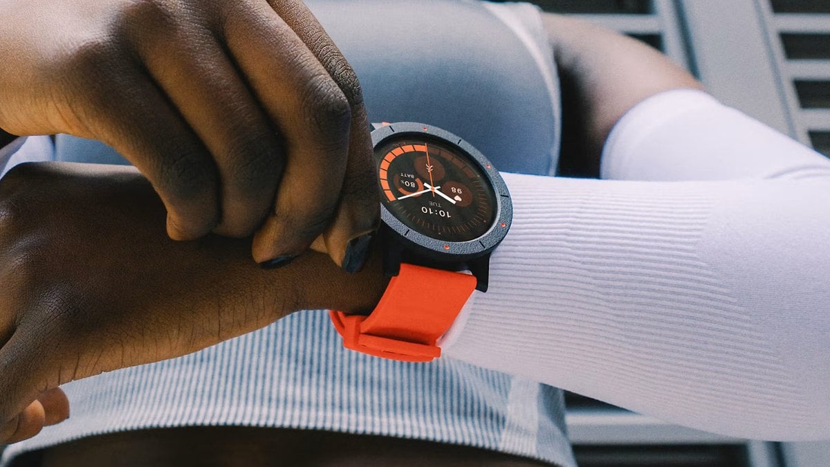 Gros plan sur une montre connectée noire et orange au poignet, une personne l'ajustant.