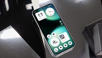 A Nothing Phone 2 displaying a green and black interface with a clock and app icons.