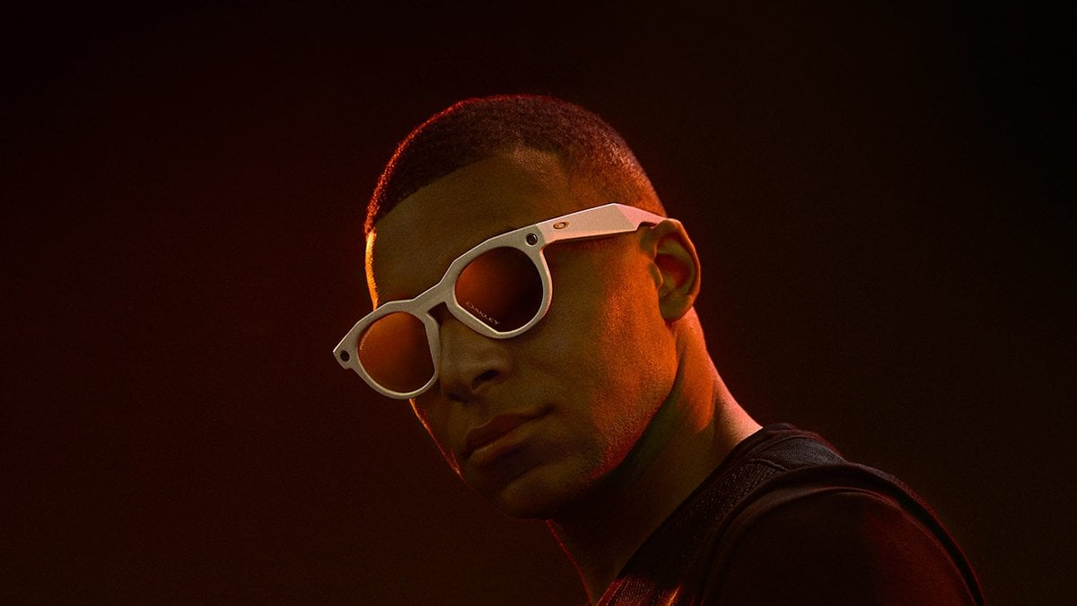 Une personne portant des lunettes de soleil blanches sur un fond sombre.