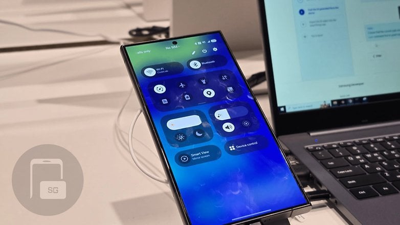 Un Samsung Galaxy S24 Ultra affichant l'interface du centre de contrôle à côté d'un ordinateur portable.