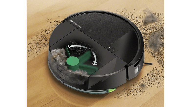 Irobot Roomba porszívó egy fa padlón, por és törmelék veszi körül.