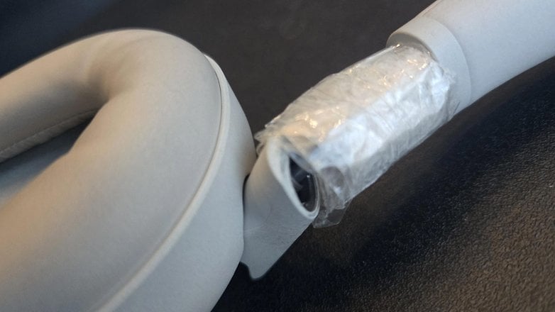 Close-up of Sony WH-1000XM6 headphones with a white ear cushion and part of the headband taped. Close-up of Sony WH-1000XM6 headphones with a white ear cushion and part of the headband taped.