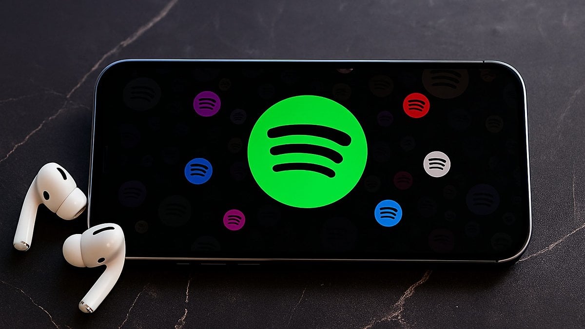 Un smartphone affichant le logo Spotify avec des AirPods à côté.