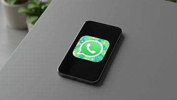 A smartphone on a table displaying the WhatsApp logo.