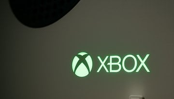 Close-up of an illuminated green Xbox logo on a console.