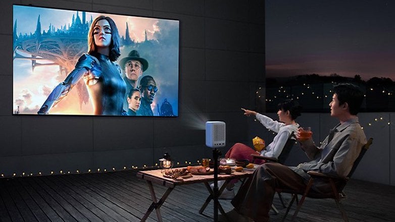 Ein Paar schaut abends draußen einen Film mit dem Projector Mini