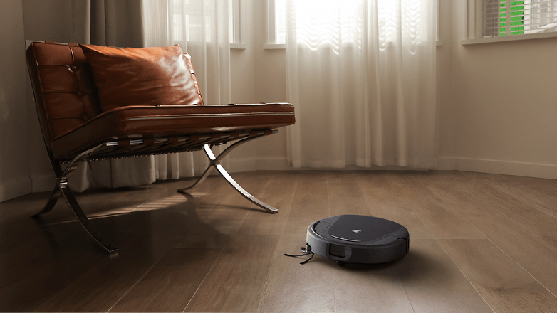 Ein Roboterstaubsauger auf einem Holzboden neben einem modernen Stuhl in einem gut beleuchteten Raum. Ein Roboterstaubsauger auf einem Holzboden neben einem modernen Stuhl in einem gut beleuchteten Raum.