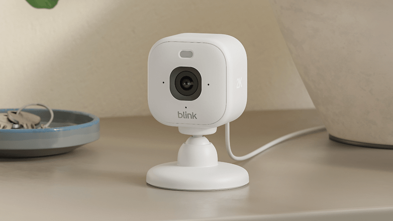Eine Blink Mini 2K+ Sicherheitskamera auf einem Tisch neben einer Schale mit Schlüsseln.